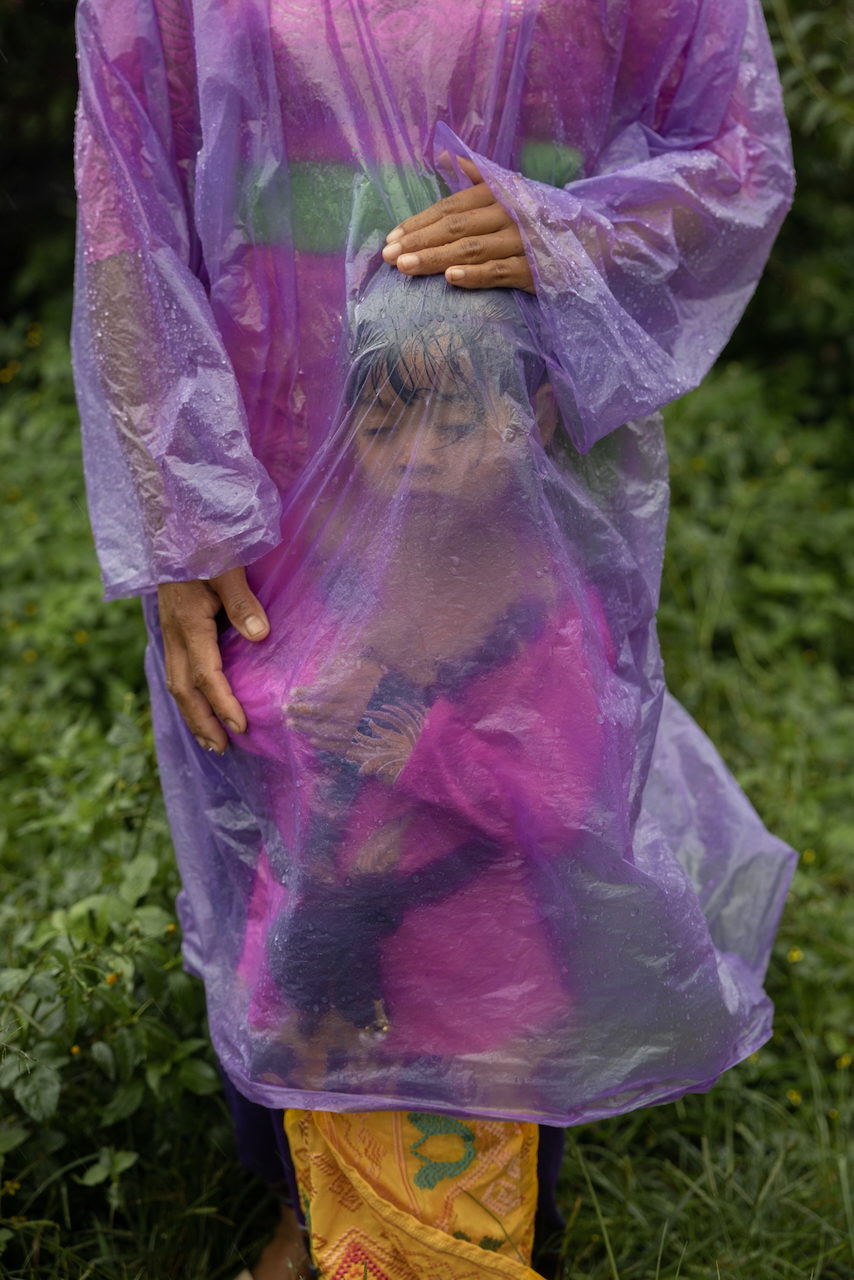 A child stands wrapped in a purple plastic poncho.
