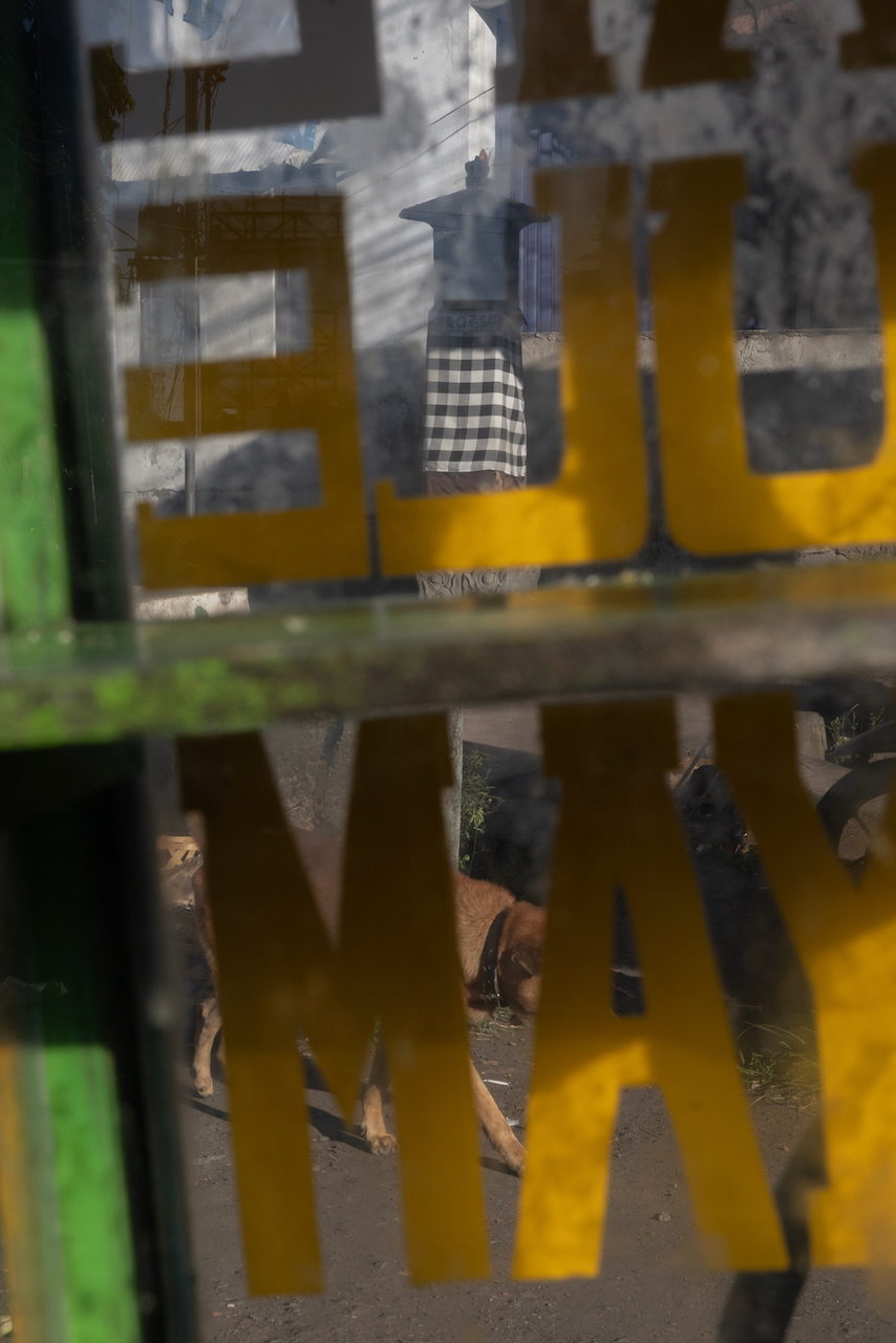 Yellow letters on a gate, checked cloth beyond.