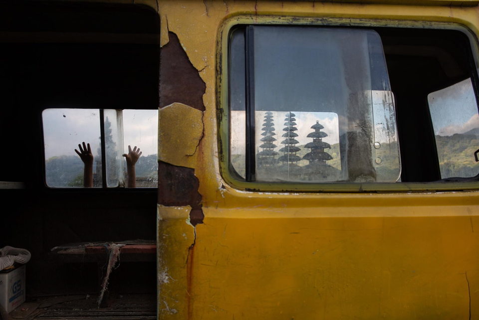 A temple decal on the window of a rusting yellow bus.