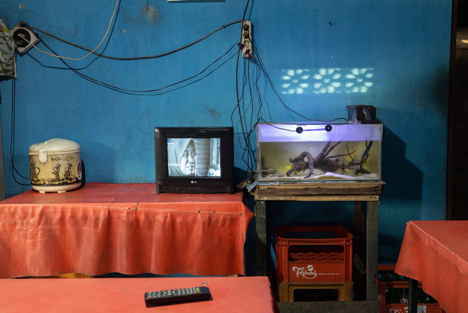 A television beside an illuminated aquarium on an orange cloth.