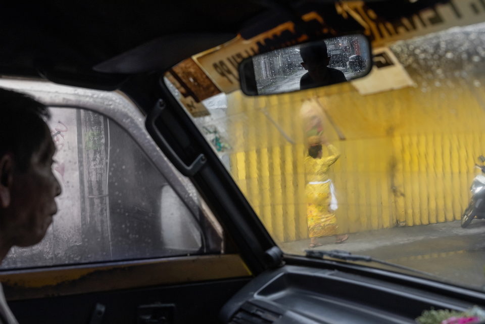 A view through a windscreen to a yellow truck and a hanging offering.